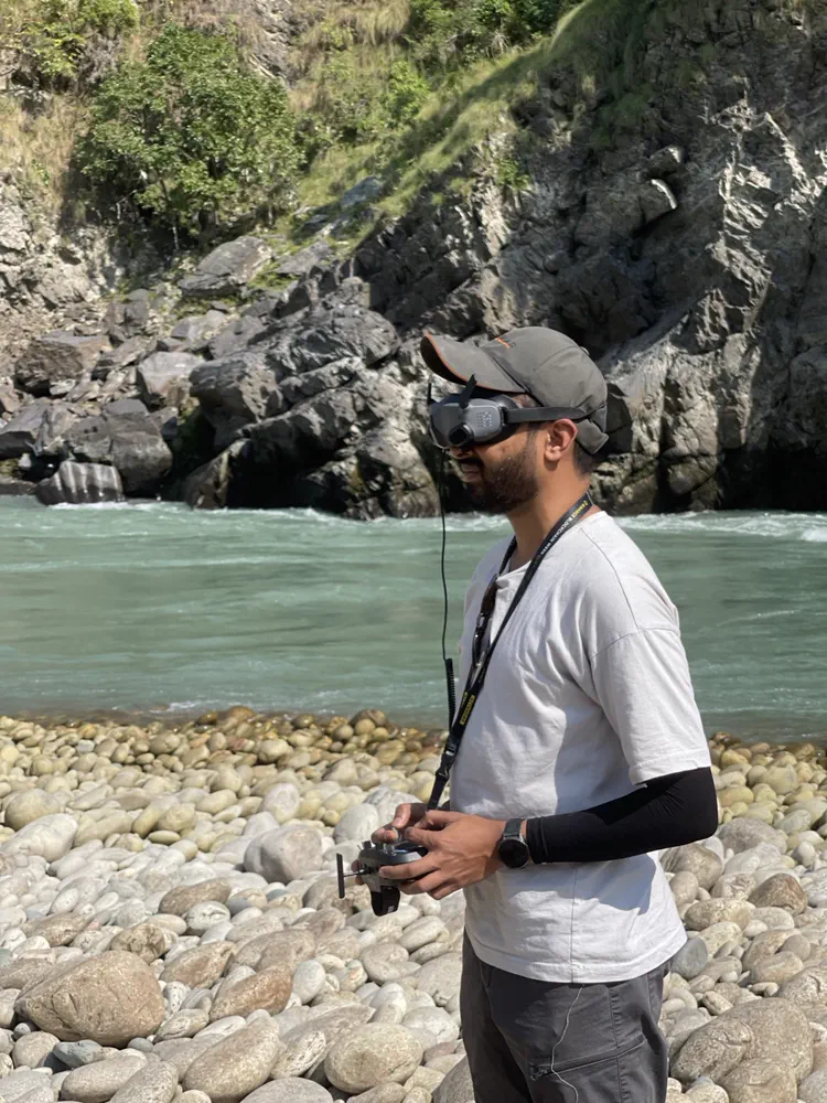 Flying FPV in goggles beside a turquoise river